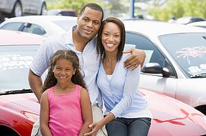 Mother and father with young daughter shopping for a new car