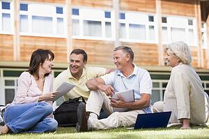Adult students on lawn of school studying and talking