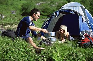 Couple outdoors at campsite with pots smiling (selective focus)