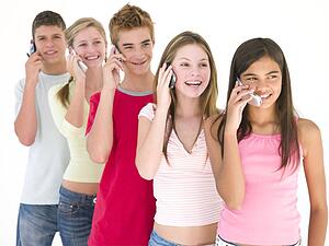 Row of five friends on cellular phones smiling