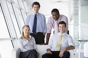 Four businesspeople in office lobby smiling