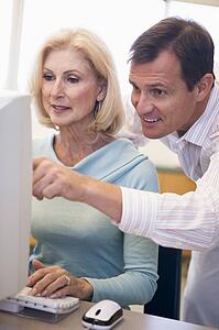 Man and woman at computer typing and pointing (high key)