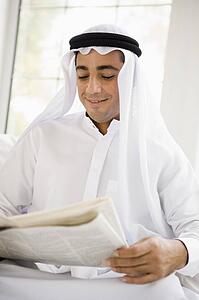 Man sitting indoors with newspaper smiling (high key/selective focus)