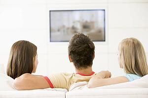 Three friends in living room watching television