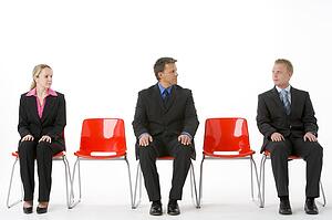 Three Business People Sitting On Red Plastic Seats 