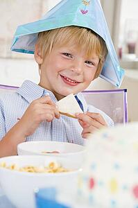 Young boy at party sitting at table with a sandwich smiling