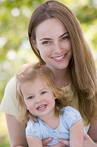 Mother holding daughter outdoors smiling