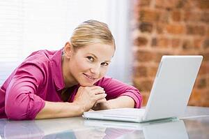 Businesswoman sitting in office with laptop smiling