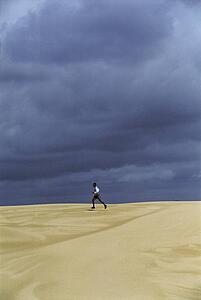 Man outdoors running in the desert (far away)