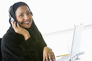 Woman wearing headset with laptop smiling (high key/selective focus)