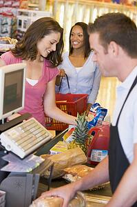 Women paying for purchases at a grocery store