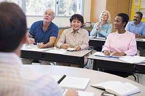 Adult students in class with teacher (selective focus)
