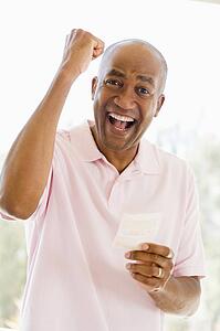 Man with winning lottery ticket excited and smiling