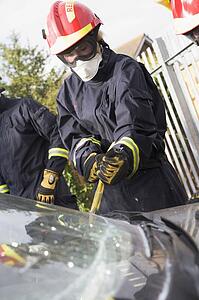 Two firefighters cutting out a windshield after an accident