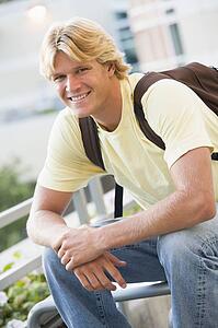 Man sitting outdoors on bench smiling (selective focus)