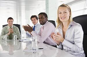 Four businesspeople in a boardroom applauding
