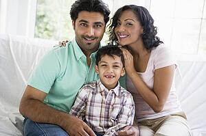 Family in living room sitting on sofa smiling (high key)