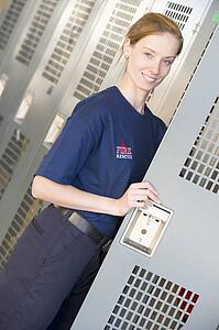 Firewoman holding her locker door open in fire station locker room (depth of field)