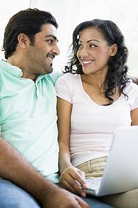 Couple in living room with laptop smiling (high key/selective focus)