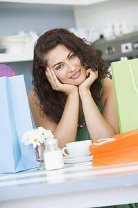 Young woman sitting at a table taking a break from shopping and drinking tea