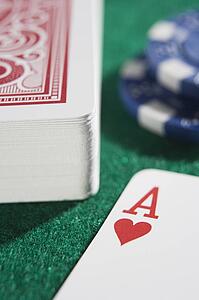 Deck of cards and poker chips on a poker table with ace of hearts showing (close up/selective focus)