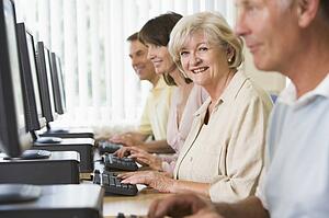 Four people sitting at computer terminals (selective focus/high key)
