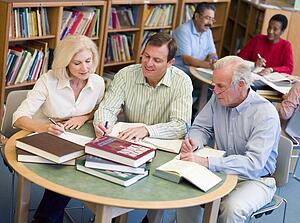 Three people in library with notepads (selective focus)