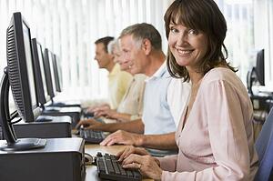 Four people sitting at computer terminals (depth of field/high key)