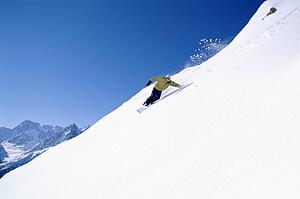 Snowboarder coming down snowy hill