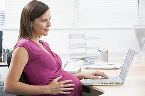 Pregnant woman at work using laptop