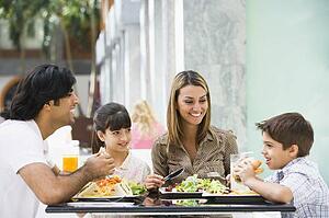 Family at restaurant eating and smiling (selective focus)