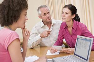 Doctor with laptop and couple in doctor's office frowning