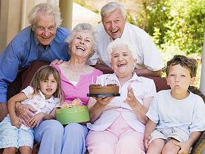 Grandparents and grandchildren on patio with cake and gift smiling