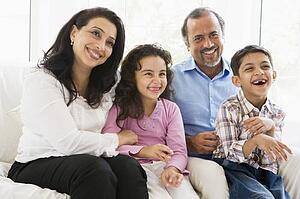 Grandparents sitting in living room with grandchildren smiling (high key)