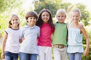 Five young friends standing outdoors smiling