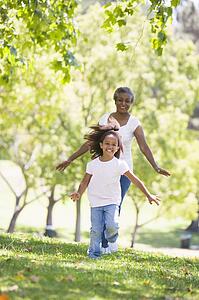 Grandmother and granddaughter running in park and smiling
