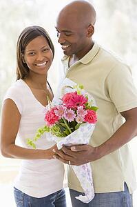 Husband and wife holding flowers and smiling