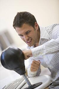 Man sitting in computer room using small punching bag for stress relief