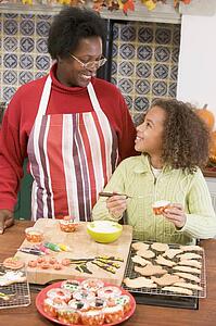 Grandmother and granddaughter making Halloween treats and smiling