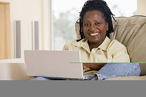 Woman in living room using laptop and smiling