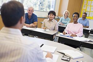 Adult students in class with teacher (selective focus)