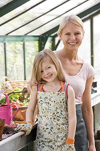 Young girl and woman in greenhouse smiling