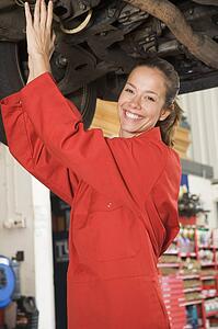 Mechanic working under car smiling