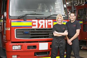 Two firefighters standing in front of fire engine