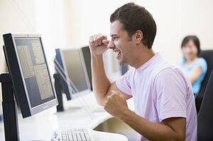 Man in computer room cheering and smiling