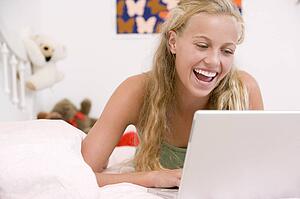 Teenage Girl Lying On Her Bed Using Laptop