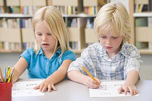 Two students in class learning letters