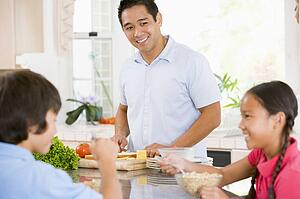 Children Having Breakfast While Dad Prepares Food