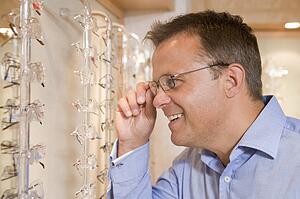 Man trying on eyeglasses at optometrists smiling