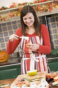 Woman in kitchen making Halloween treats and smiling